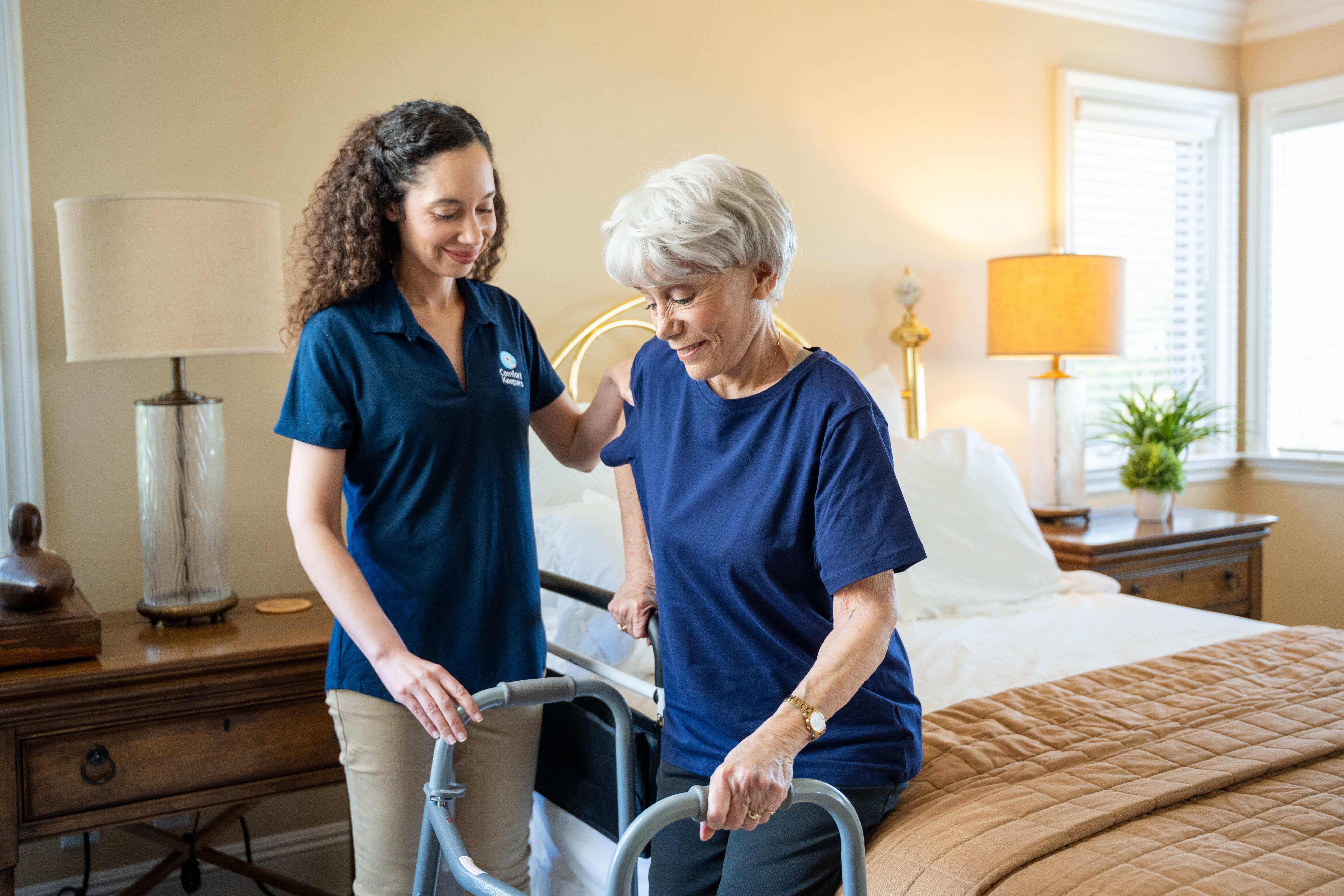 Comfort Keepers caregiver assisting a senior client with a walker in their bedroom